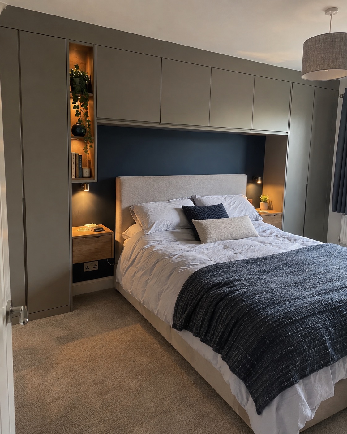 Dark grey fitted bedroom wardrobes surrounding a bed with integrated lighting