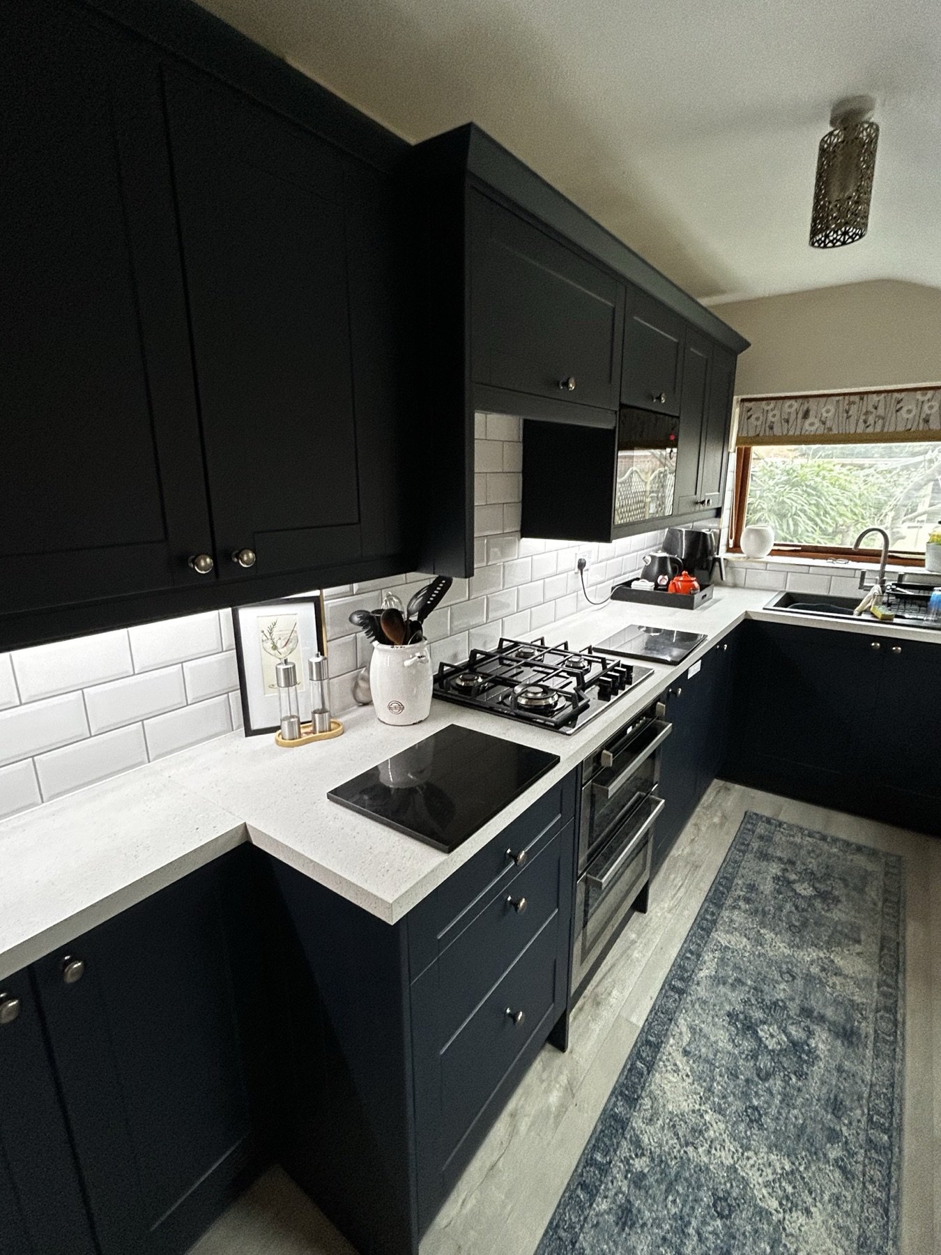 Deep navy in-frame Shaker kitchen with white metro tiles and quartz worktops
