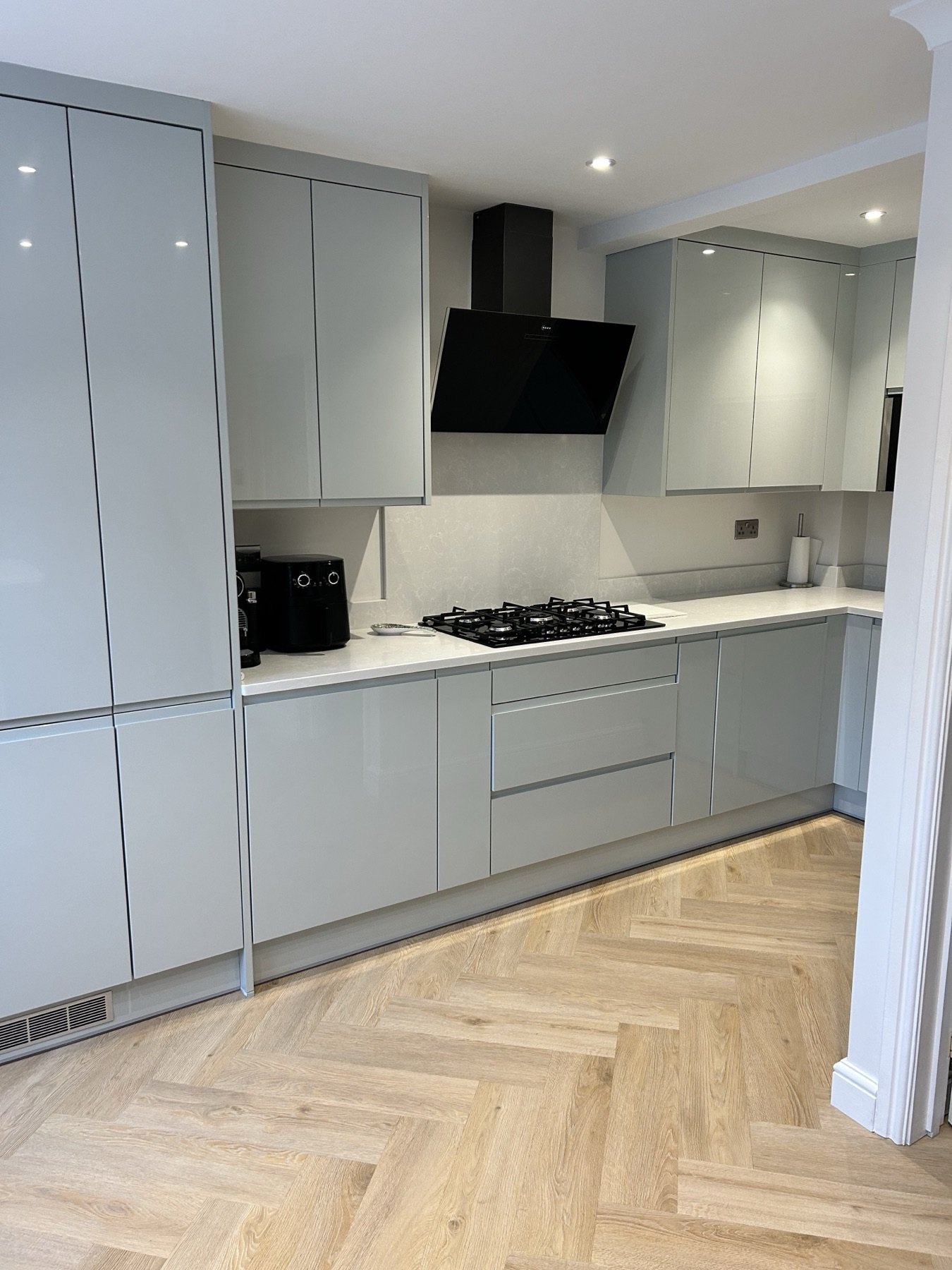 Handleless gloss kitchen with herringbone oak floor by TLS Kitchens
