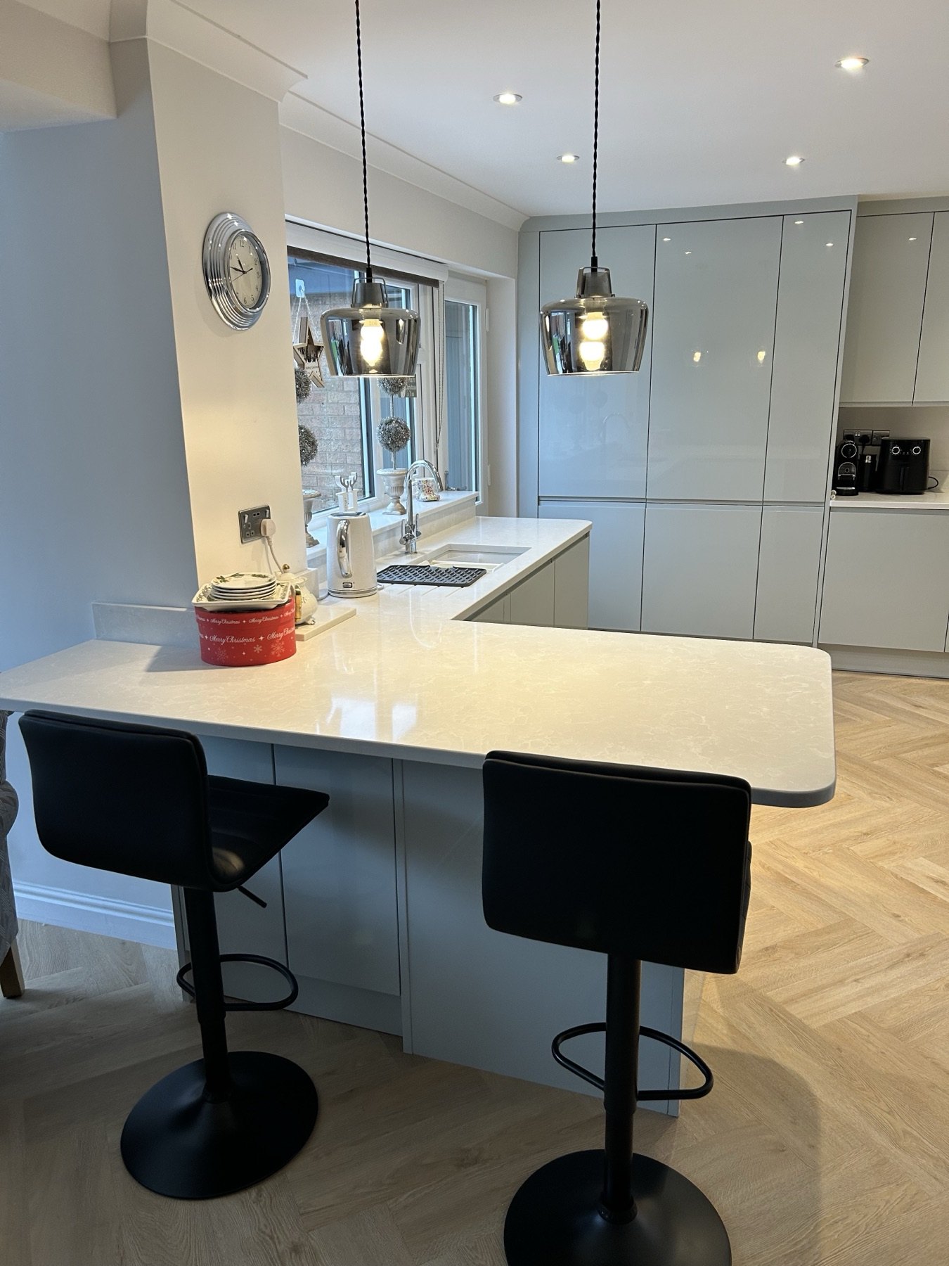 Grey handleless kitchen with island and herringbone oak floor