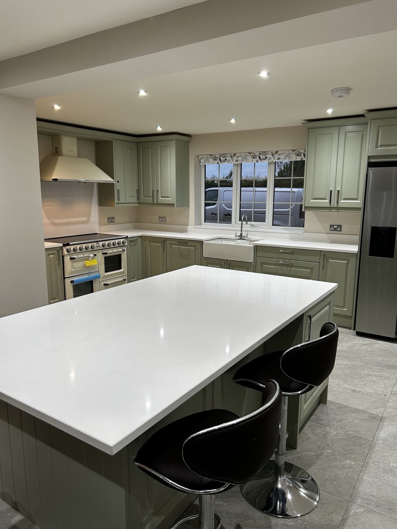 Sage green in-frame kitchen with island seating and quartz worktops