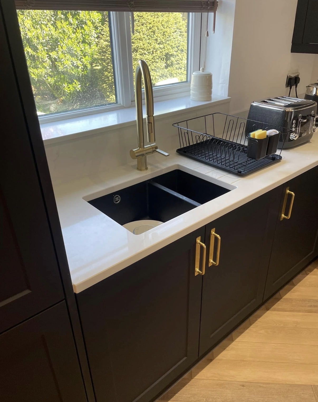 Genuine TLS Kitchens fitted light worktop with a black undermount sink, brass tap and dark cabinets